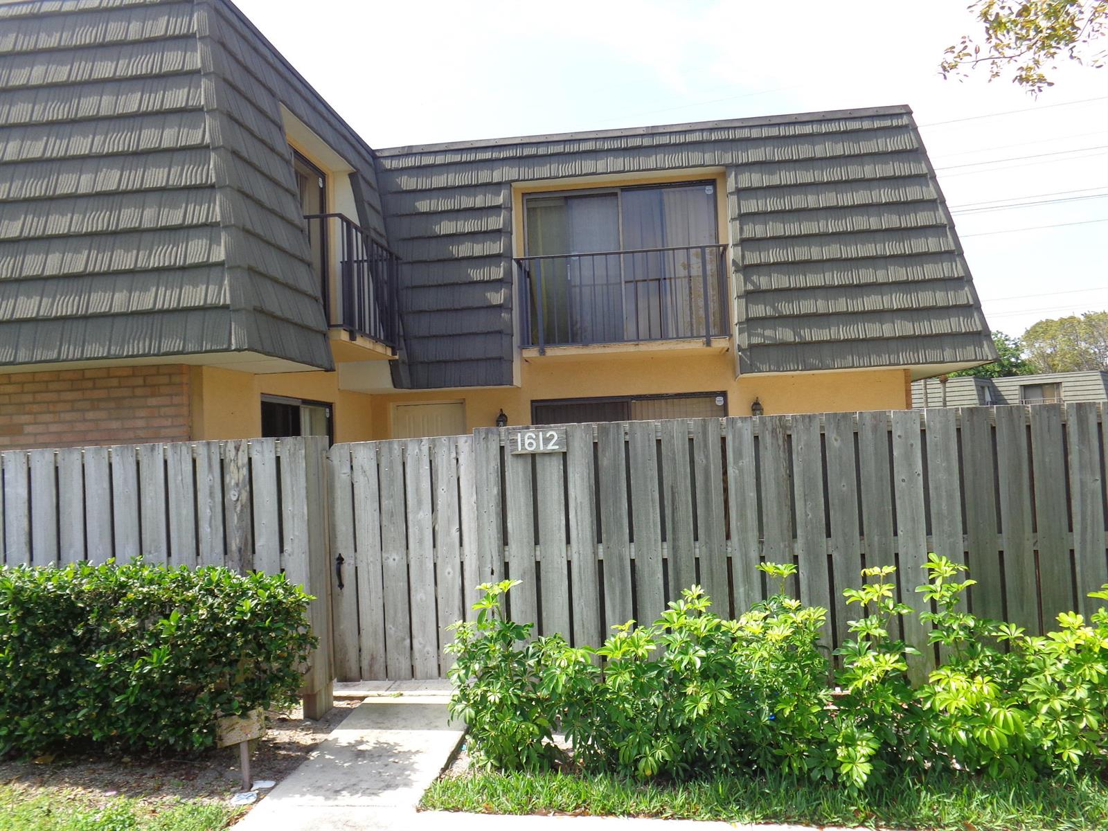 A two-story residential building with a mansard roof and a wooden privacy fence — 1612 16th Way # 1612, West Palm Beach FL 33407, WEST PALM BEACH, FL