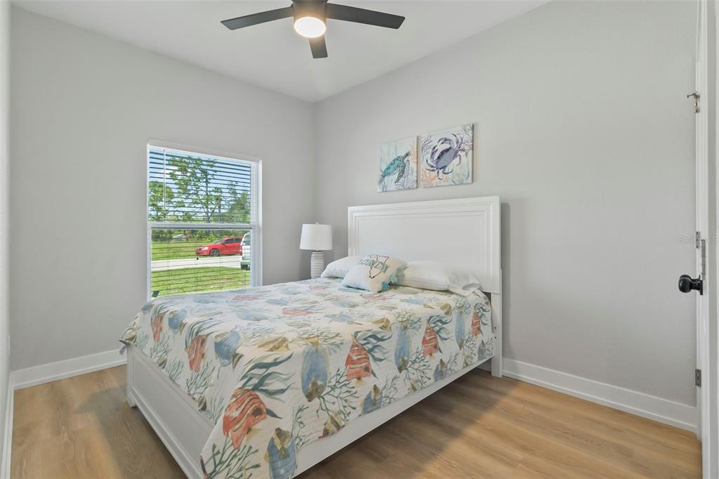 A bedroom with light wood flooring, a white bed frame, and a ceiling fan — 9155 AGATE STREET UNIT 9155, PORT CHARLOTTE, FL