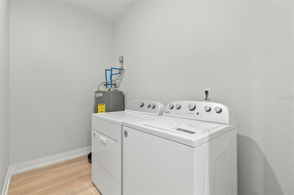 A laundry room features a white washer and dryer next to a water heater — 9155 AGATE STREET UNIT 9155, PORT CHARLOTTE, FL