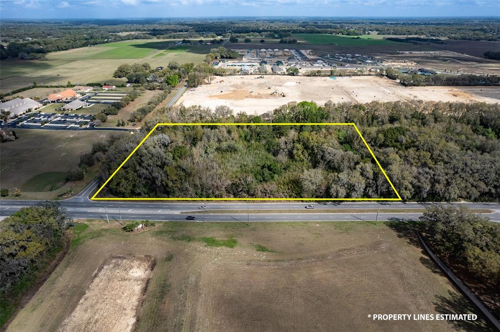 An aerial view shows a rectangular, wooded plot of land bordered by a highway — 7415 SE HIGHWAY 42, SUMMERFIELD, FL