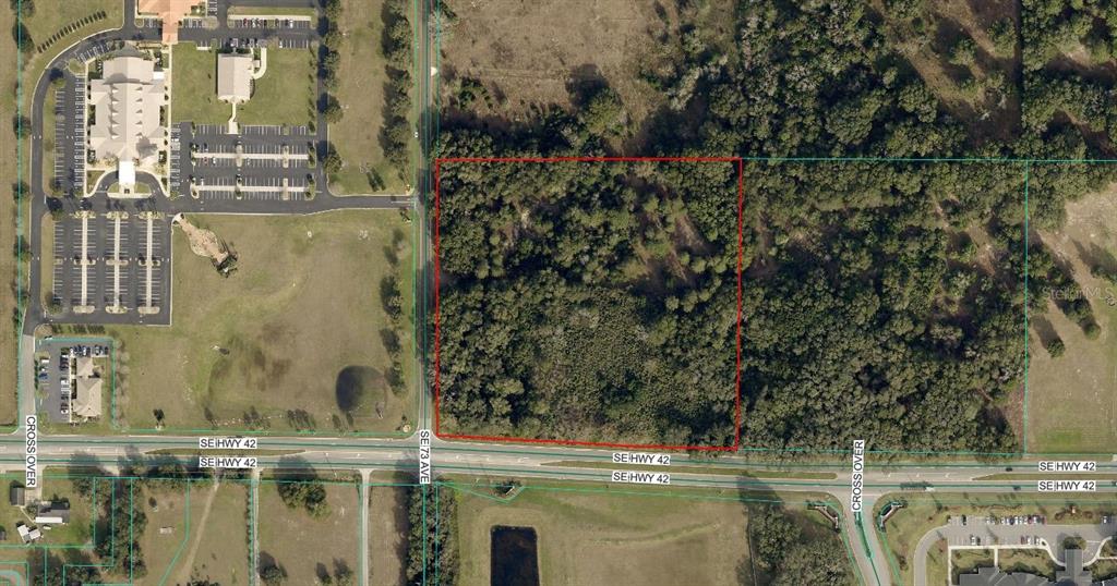 This aerial map shows a rectangular wooded lot bordered by a highway and commercial buildings — 7415 SE HIGHWAY 42, SUMMERFIELD, FL