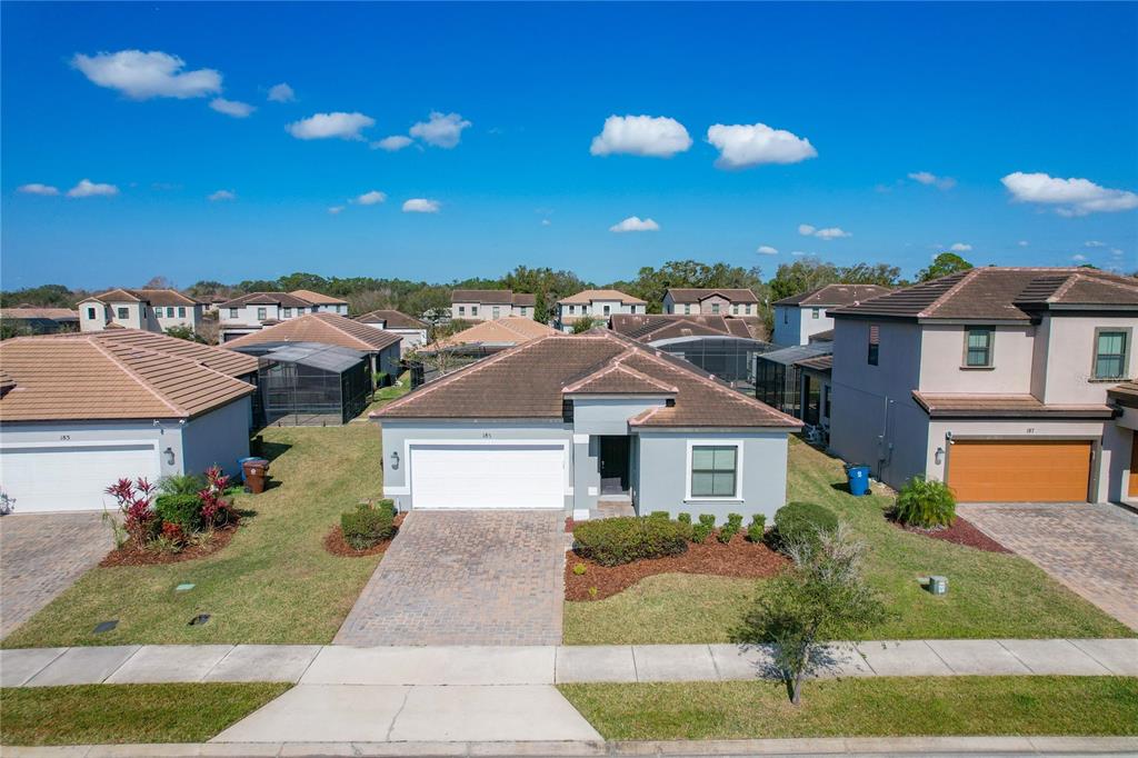 A single-story suburban house with a paved driveway, a two-car garage, and a tiled roof — 185 BROOKES PLACE, HAINES CITY, FL