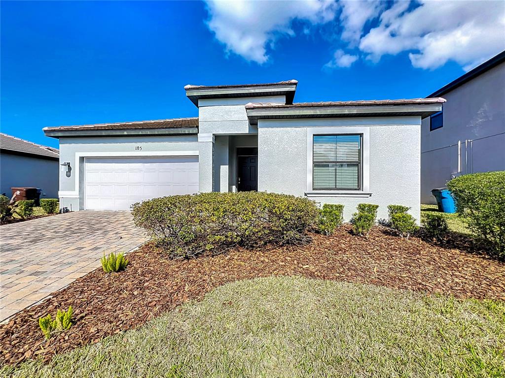 A single-story house with a white exterior, a two-car garage, and a landscaped front yard — 185 BROOKES PLACE, HAINES CITY, FL