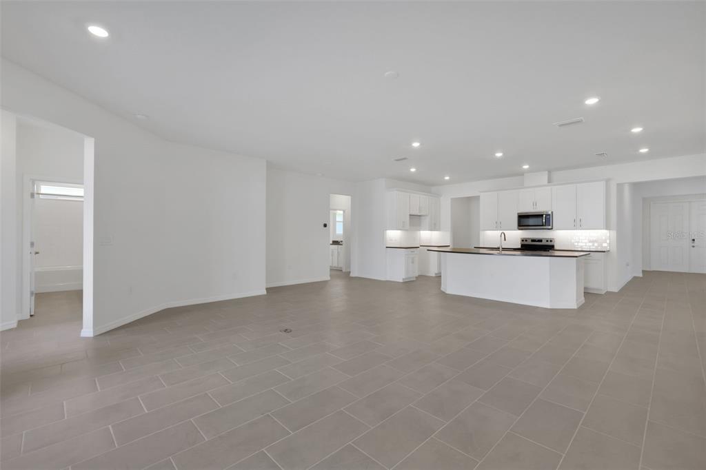 A spacious, open-concept kitchen and living area features white cabinetry, a central island, and tile flooring — 17534 VALLEYWOOD PARKWAY, LAND O LAKES, FL