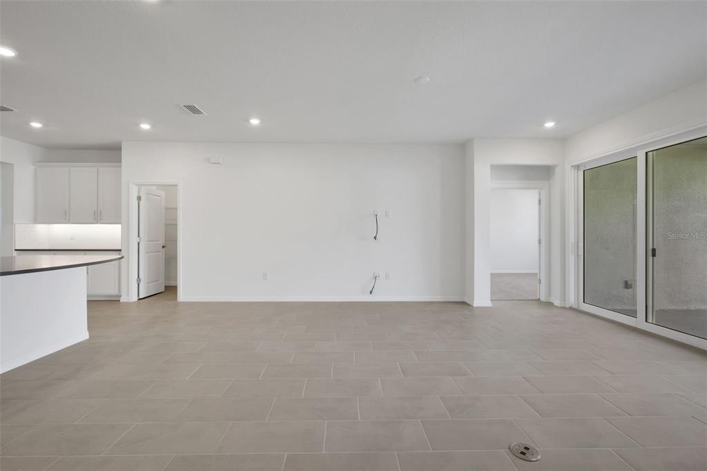 A spacious, minimalist living area features light gray tile flooring, white walls, and sliding glass doors — 17534 VALLEYWOOD PARKWAY, LAND O LAKES, FL