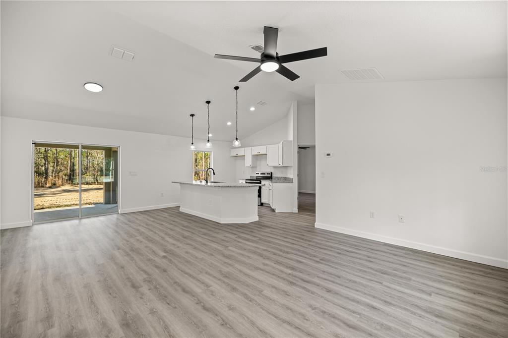 A kitchen island with a granite countertop and pendant lighting sits in a white room — 24125 NW FOXGLOVE LANE, DUNNELLON, FL