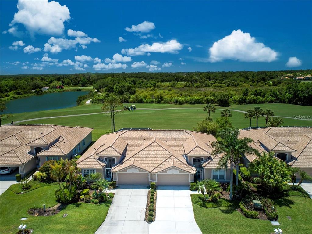 A covered patio overlooks a swimming pool and a green golf course landscape — 4383 SAMOSET DRIVE, SARASOTA, FL