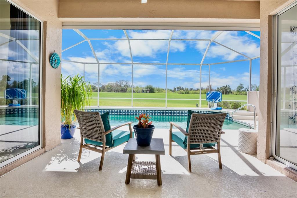 A screened-in swimming pool overlooks a grassy golf course under a blue sky — 4383 SAMOSET DRIVE, SARASOTA, FL