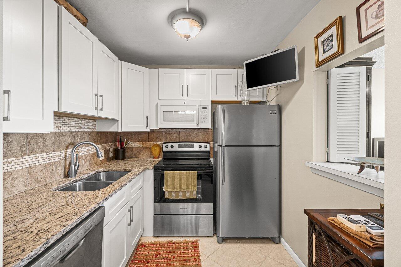 A kitchen features white cabinets, granite countertops, stainless steel appliances, and a tiled backsplash — 175 Suffolk E, Boca Raton FL 33434, BOCA RATON, FL