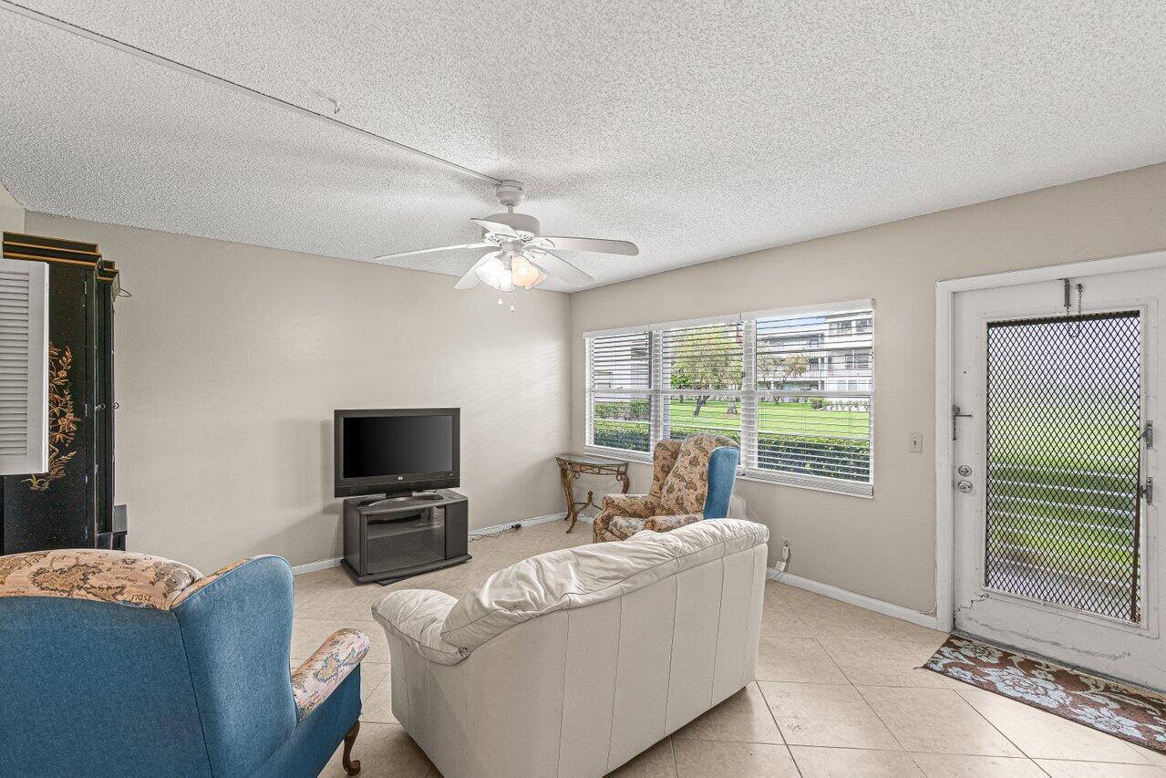 A living room features a white sofa, two blue armchairs, a television, and tile flooring — 175 Suffolk E, Boca Raton FL 33434, BOCA RATON, FL