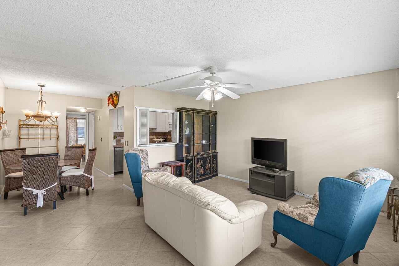 A living room with tile floors, a white sofa, blue armchairs, and a dining area — 175 Suffolk E, Boca Raton FL 33434, BOCA RATON, FL