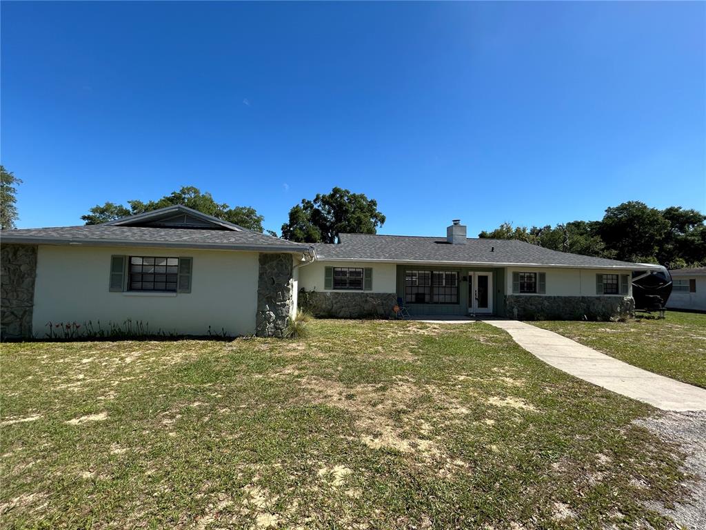 A single-story house with a stone facade, light-colored walls, and a concrete walkway — 8801 E CRESCO LANE, INVERNESS, FL