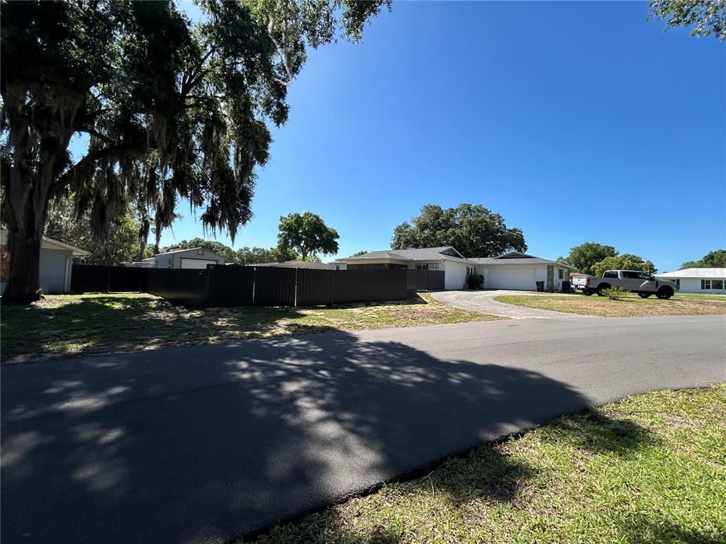A single-story house with a driveway and a black privacy fence under a clear sky — 8801 E CRESCO LANE, INVERNESS, FL