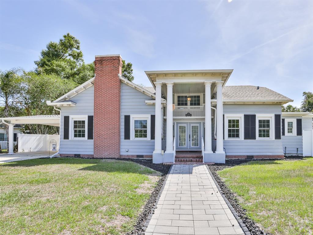 A light blue house with a brick chimney and a columned front porch entrance — 915 KISSENGEN AVENUE, BARTOW, FL