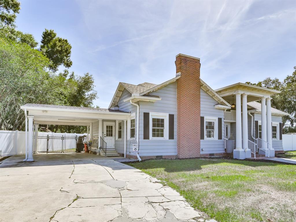 A light blue house with a brick chimney, a carport, and a front porch with columns — 915 KISSENGEN AVENUE, BARTOW, FL