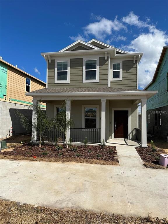 A two-story house features olive-green siding, a covered front porch, and a concrete driveway — 6014 BLISSFUL STREET, CLERMONT, FL