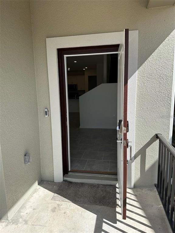 An open front door reveals a tiled entryway leading into an interior living space — 6014 BLISSFUL STREET, CLERMONT, FL