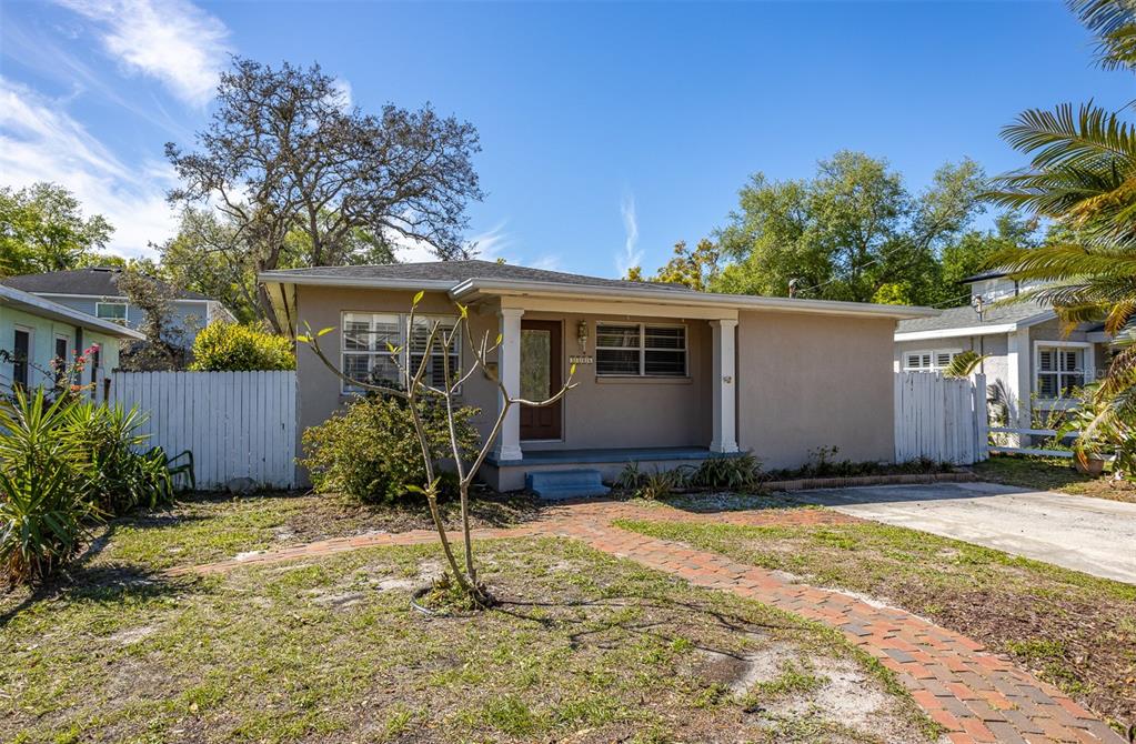 A single-story tan house with a front porch, brick walkway, and white picket fence — 3306 W FIELDER STREET, TAMPA, FL