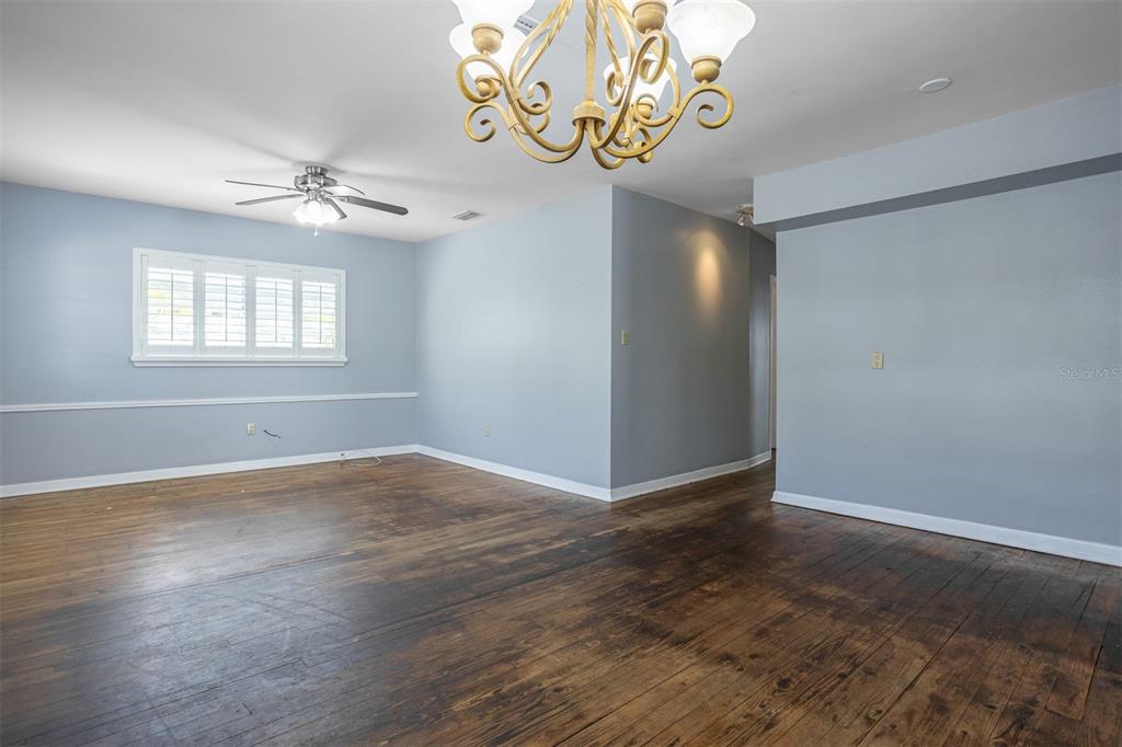 An empty room features hardwood floors, light blue walls, a ceiling fan, and a chandelier — 3306 W FIELDER STREET, TAMPA, FL