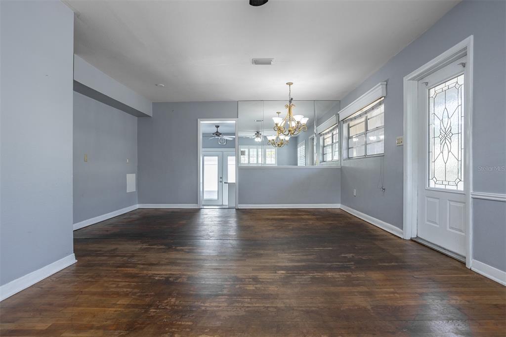 An empty room features hardwood floors, gray walls, a mirrored wall, and a chandelier — 3306 W FIELDER STREET, TAMPA, FL