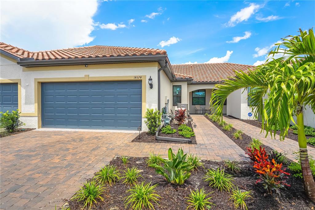A single-story house with a blue garage door, tile roof, and a paved walkway — 14574 MOSSY PINE COURT, NOKOMIS, FL
