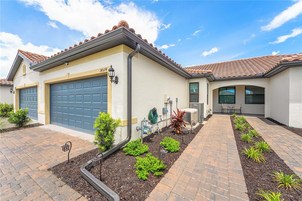 A single-story house exterior features a paved walkway, a garage, and a tiled roof — 14574 MOSSY PINE COURT, NOKOMIS, FL