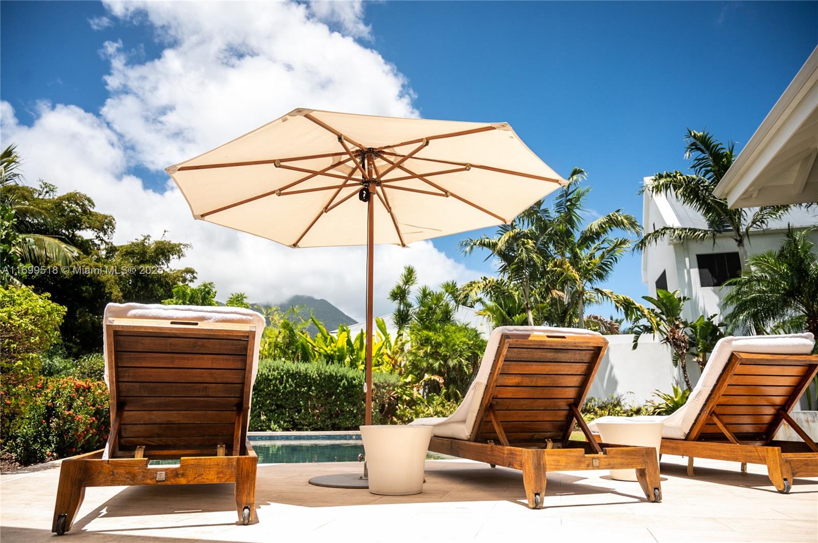 Three wooden lounge chairs sit on a patio under a large umbrella by a pool — 2015 Villas at Pinney's Beach # 2015, MN 56467, MN