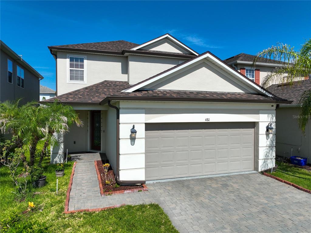 A two-story house features a beige stucco exterior, a paved driveway, and a two-car garage — 480 ROCKY GROVE LANE, SANFORD, FL