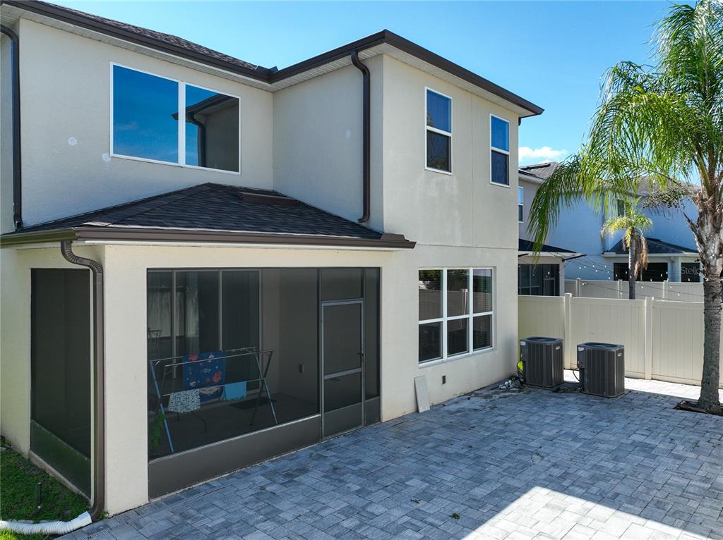 A two-story house exterior features a screened-in patio, paver patio, and two air conditioning units — 480 ROCKY GROVE LANE, SANFORD, FL