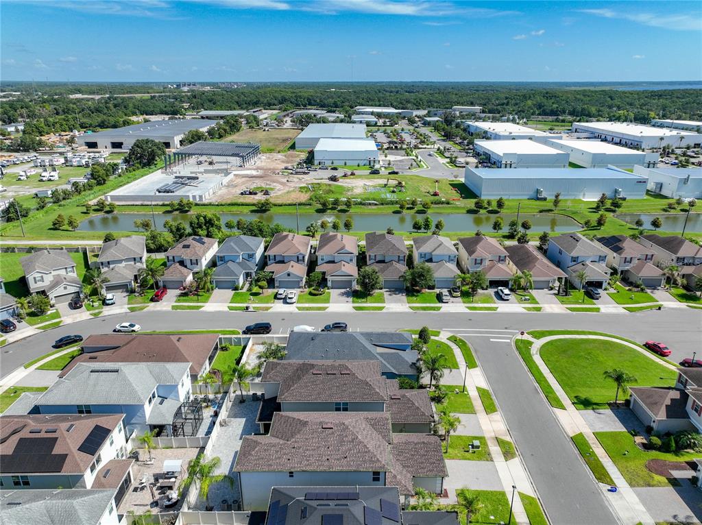 An aerial view shows a suburban neighborhood with houses, a pond, and nearby industrial warehouses — 480 ROCKY GROVE LANE, SANFORD, FL