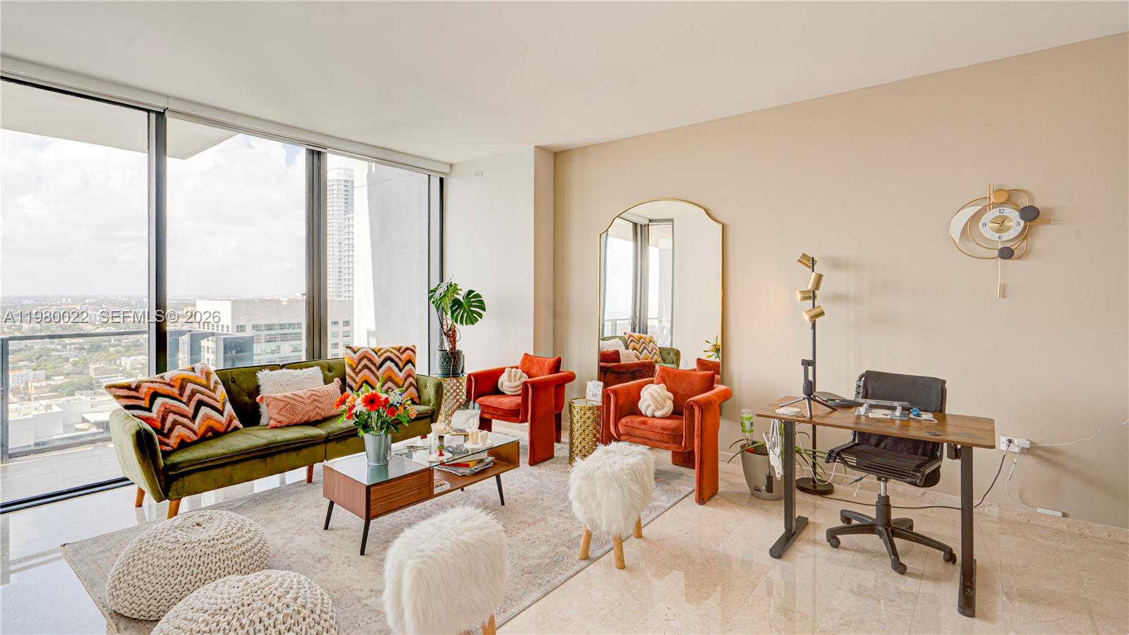 A modern living room features an olive green sofa, orange armchairs, and floor-to-ceiling windows — 88 SW 7th St # 2706, Miami FL 33130, MIAMI, FL