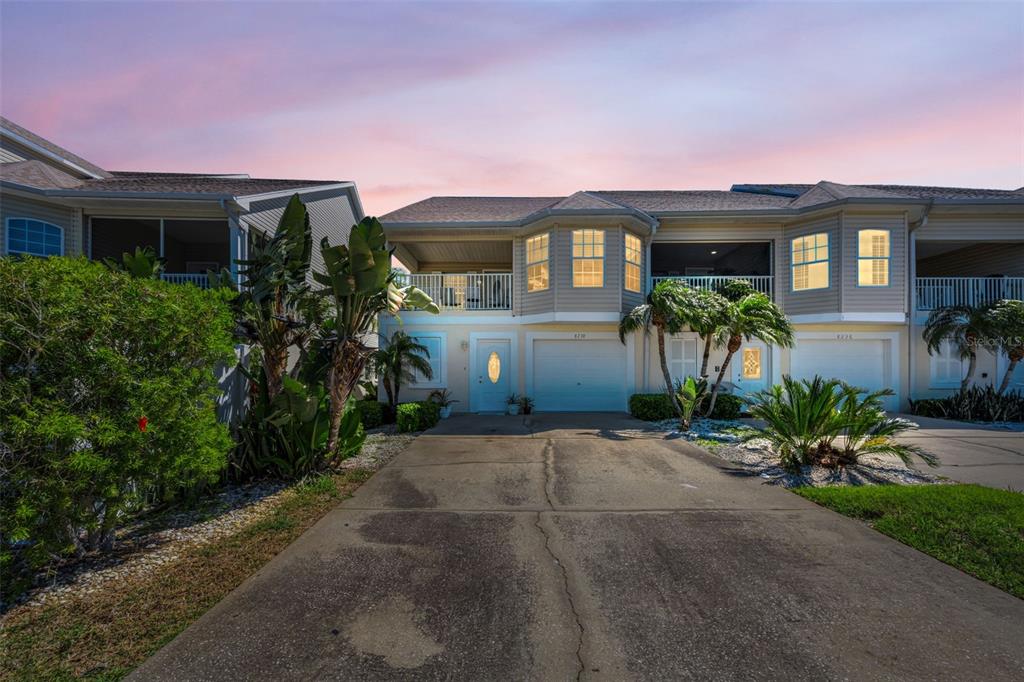A two-story townhouse exterior features a concrete driveway, a garage, and a second-floor balcony — 8238 AQUILA STREET, PORT RICHEY, FL
