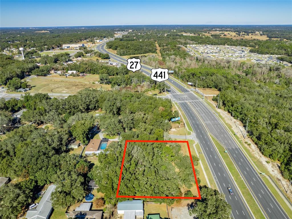 An aerial view shows a rectangular wooded lot outlined in red next to a highway — 0000 US HWY 27/441, FRUITLAND PARK, FL