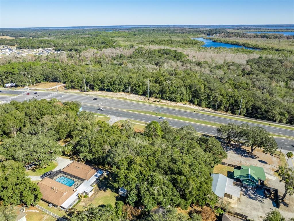 An aerial view shows a house with a pool, a nearby building, and a highway — 0000 US HWY 27/441, FRUITLAND PARK, FL