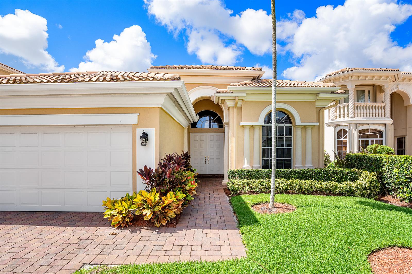 A beige house with a white garage door, arched windows, and a brick walkway — 8102 Valhalla Drive, Delray Beach FL 33446, DELRAY BEACH, FL