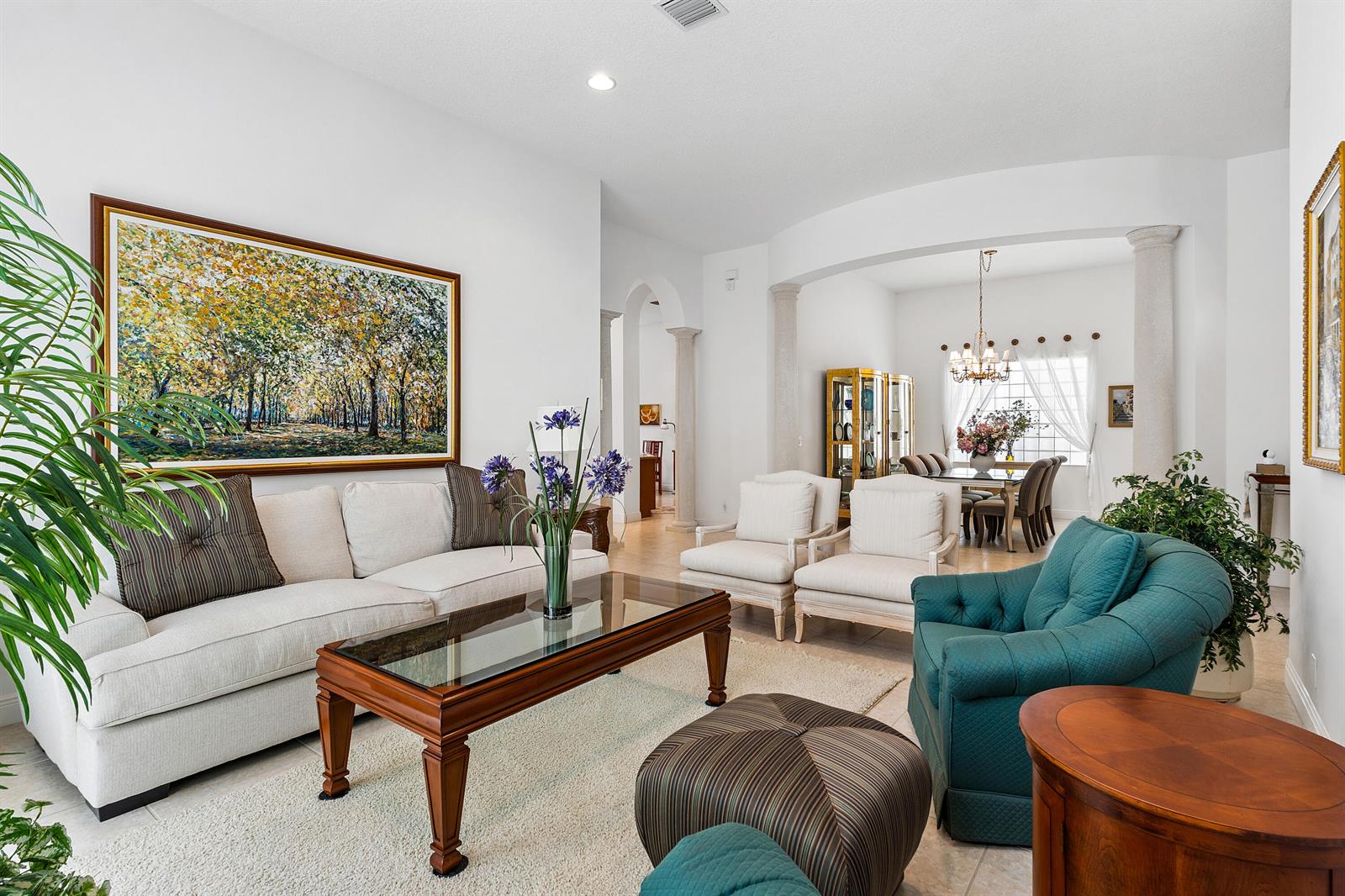 A spacious living room features a white sofa, teal armchair, and a dining area beyond — 8102 Valhalla Drive, Delray Beach FL 33446, DELRAY BEACH, FL