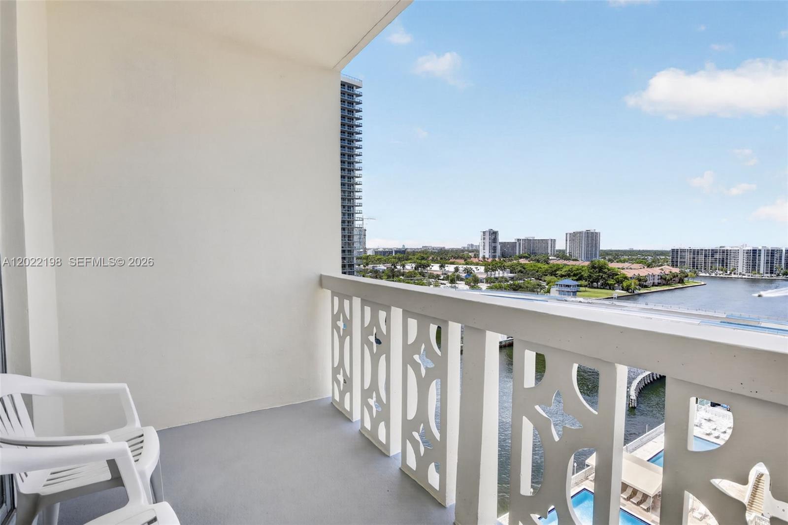 A balcony with white decorative railings overlooks a waterway and city skyline — 1817 S Ocean Dr # 19, Hallandale Beach FL 33009, HALLANDALE BEACH, FL