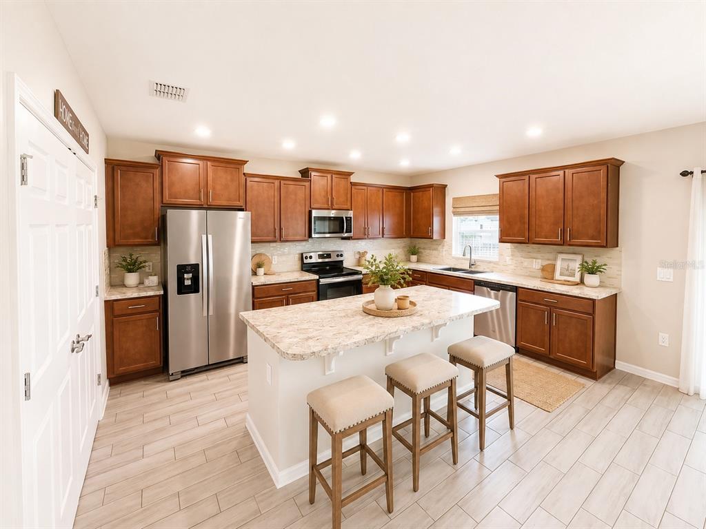 A kitchen features wood cabinets, stainless steel appliances, a center island, and light tile flooring — 352 BLUE LAKE CIRCLE, KISSIMMEE, FL