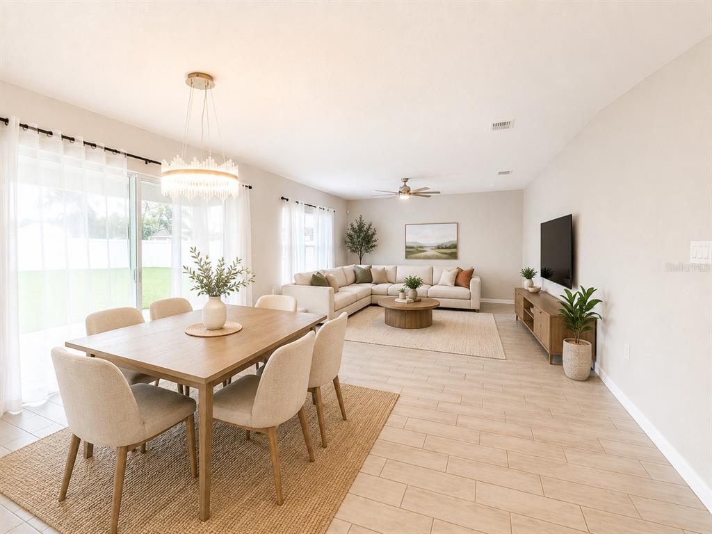 An open-concept living and dining area features light wood-look tile flooring and neutral furniture — 352 BLUE LAKE CIRCLE, KISSIMMEE, FL