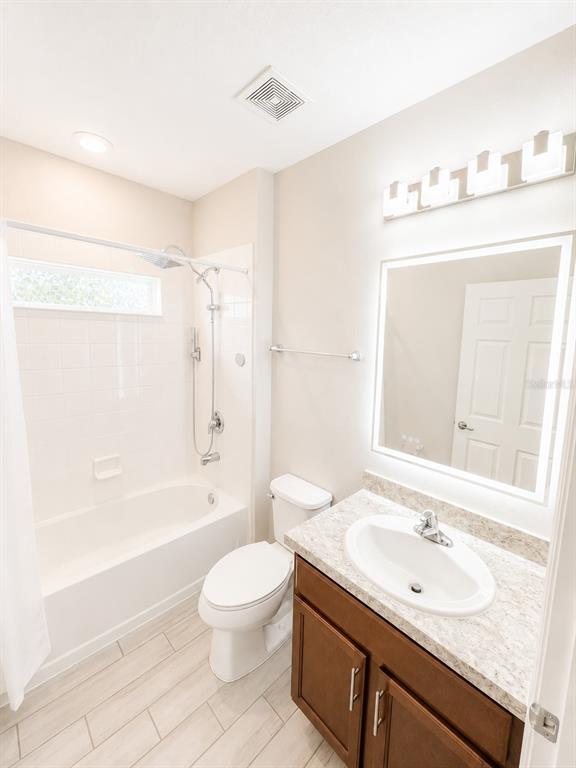 A bathroom features a tub-shower combination, a white toilet, and a vanity with a mirror — 352 BLUE LAKE CIRCLE, KISSIMMEE, FL