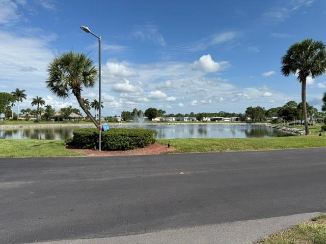 A paved road leads to a pond with a fountain and surrounding palm trees — 401 EL PRADO, NORTH PORT, FL