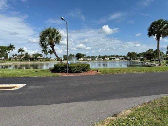 A paved road leads to a pond with a fountain and palm trees — 401 EL PRADO, NORTH PORT, FL