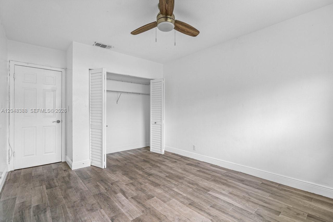 A bedroom features white walls, wood-look flooring, a ceiling fan, and a bi-fold closet door — 260 NW 19th St # 26, Boca Raton FL 33432, BOCA RATON, FL