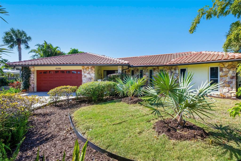 A single-story house with a red tile roof, stone facade, and a red garage door — 5456 AZURE WAY, SARASOTA, FL