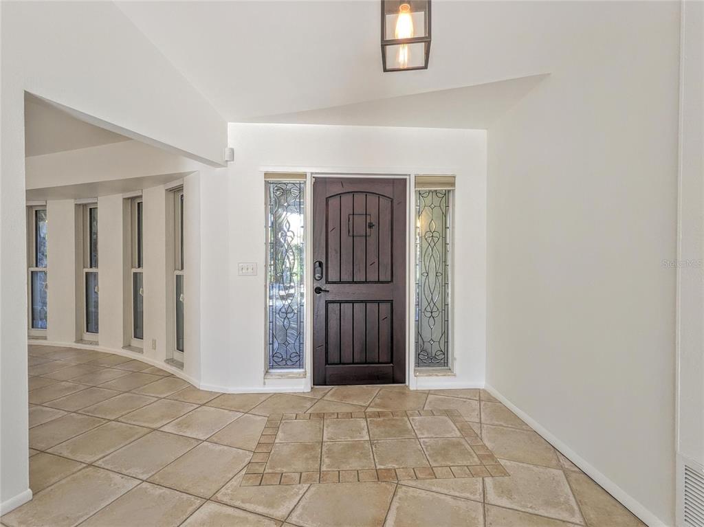 An entryway features a dark wood front door with sidelights and light-colored tile flooring — 5456 AZURE WAY, SARASOTA, FL