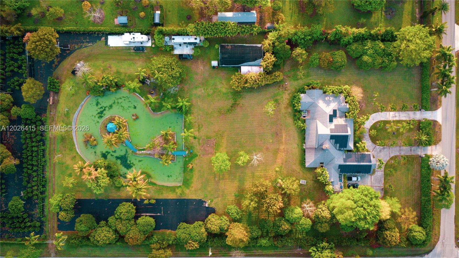 An aerial view shows a house, a pond with a bridge, and outbuildings on a lot — 20175 SW 256th St, Homestead FL 33031, HOMESTEAD, FL