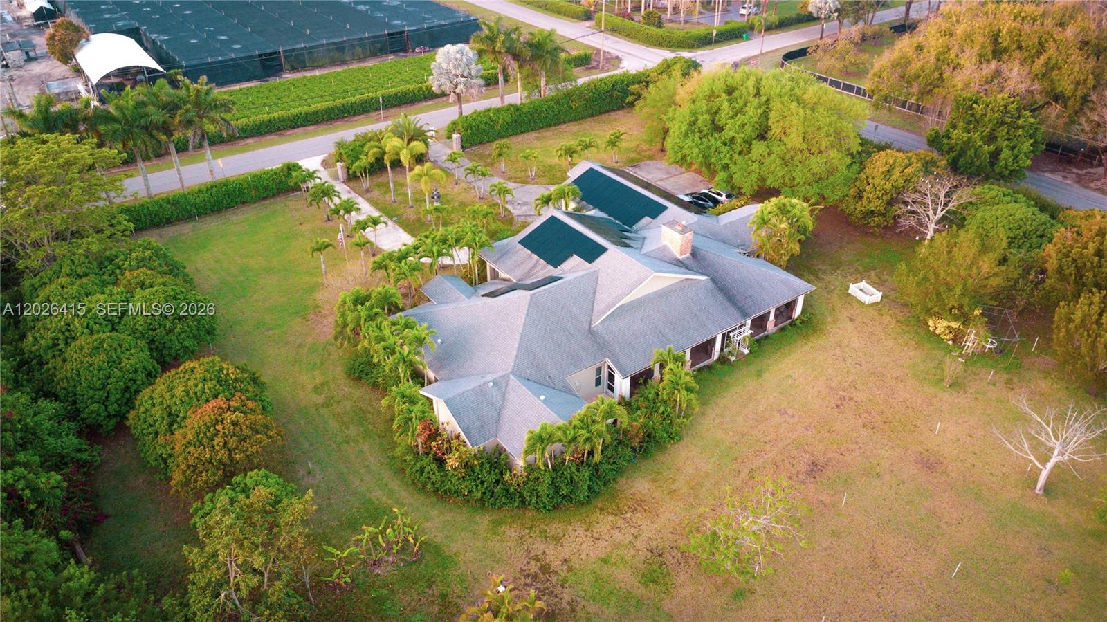 An aerial view shows a single-story house with solar panels surrounded by trees and lawns — 20175 SW 256th St, Homestead FL 33031, HOMESTEAD, FL