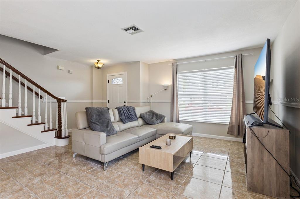 A living room features a light-colored sectional sofa, a wooden coffee table, and tiled flooring — 3125 HOLLAND DRIVE, ORLANDO, FL