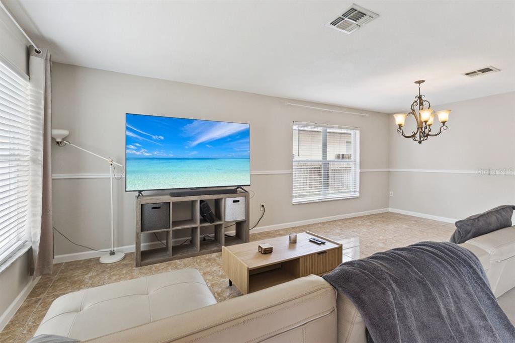 A living room features a television on a storage unit, a coffee table, and tile flooring — 3125 HOLLAND DRIVE, ORLANDO, FL