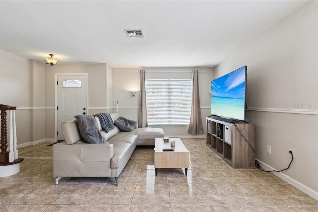A living room features a light-colored sectional sofa, a television on a stand, and tile flooring — 3125 HOLLAND DRIVE, ORLANDO, FL